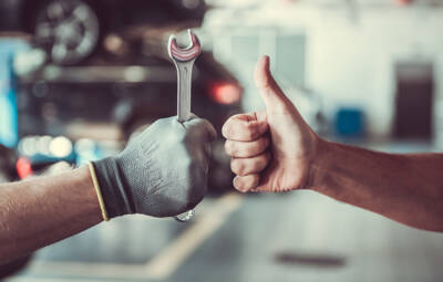 Handsome auto service workers Cropped image of mechanics working in auto service. One is holding a spanner while the other is showing Ok sign